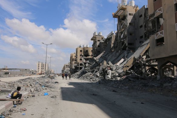 Palestinians pass the remains of buildings following the withdrawal of the Israeli military from Hamad City, west of Khan Younis, Gaza.