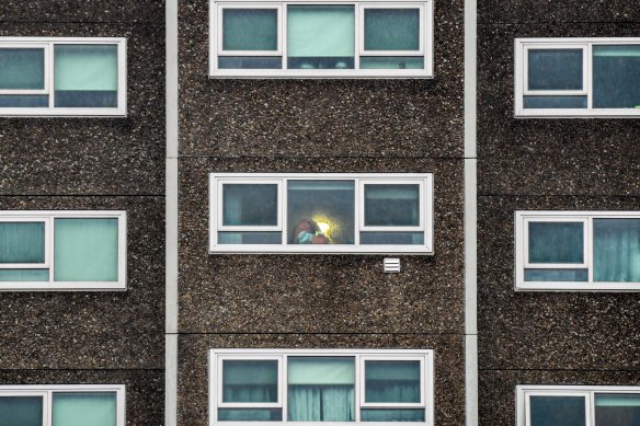 A woman looks out her window at a North Melbourne public housing tower on July 5 during the hard lockdown.