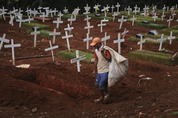 A man looks for discarded plastic near newly dug graves for those suspected of dying from COVID-19 in Jakarta, Indonesia. 