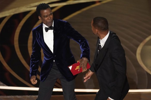 Chris Rock, left, reacts after being hit on stage by Will Smith while presenting the award for best documentary feature.