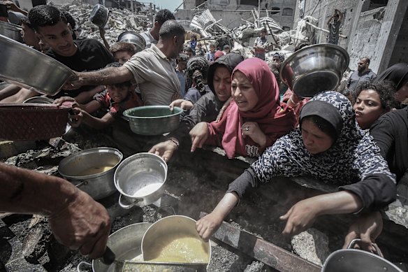 Displaced Palestinians collect cooked food from a community food kitchen in Jabaliya, northern Gaza.