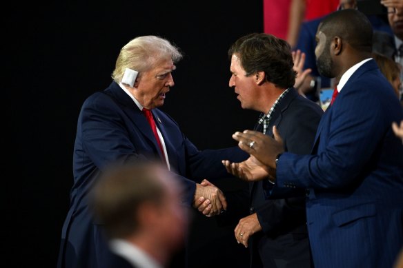 Former Fox News host Tucker Carlson welcomes Donald Trump onstage at the RNC.