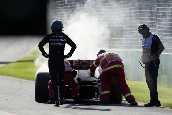 Mercedes driver George Russell, left, watches as course marshals extinguish an engine fire in his car during the Australian Formula One Grand Prix at Albert Park in Melbourne.