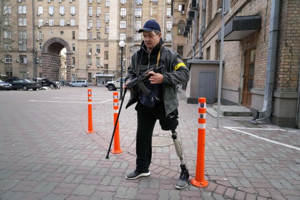 An armed civil defense man patrols an empty street due to curfew in Kyiv, Ukraine, Sunday.