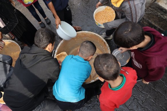 Palestinian children collect free food handouts from a volunteer hospice in Rafah, southern Gaza.