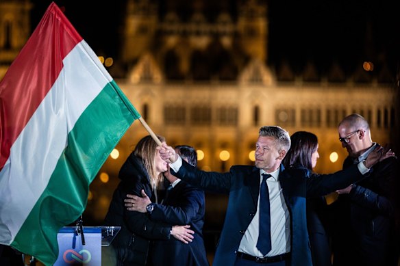 O próximo primeiro-ministro, Peter Magyar, segura uma bandeira húngara após a votação.