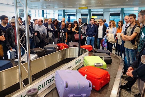 Los pasajeros esperan sus maletas en un carrusel del aeropuerto. 