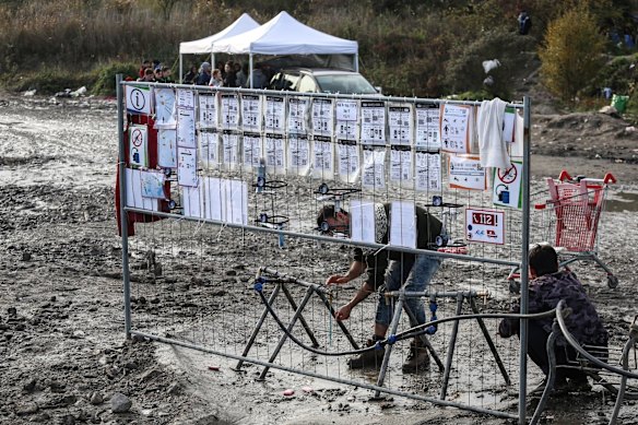 Os migrantes se lavam para uma torneira improvisada de água em um grande acampamento migrante.