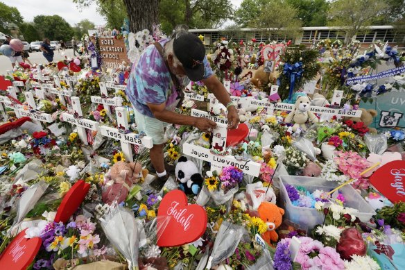 A visitor places bracelets on crosses at a memorial as he and others pay their respects to the victims killed in the Robb Elementary School shooting.