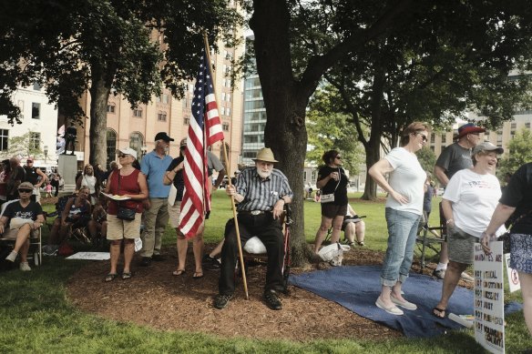 A demonstrator holds an American flag during a protest against COVID-19 vaccination mandates in Lansing, Michigan, on Friday, August 6, 2021. 