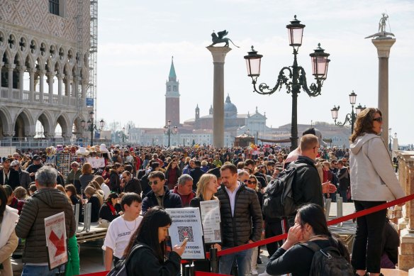 Tourists stand in line to climb the bell tower of San Marco in Venice.