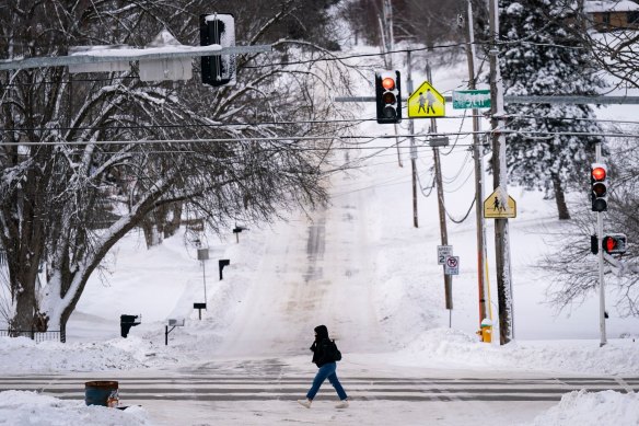 A pedestrian crosses the street during a winter storm on the day of the Iowa Caucus in Des Moines.