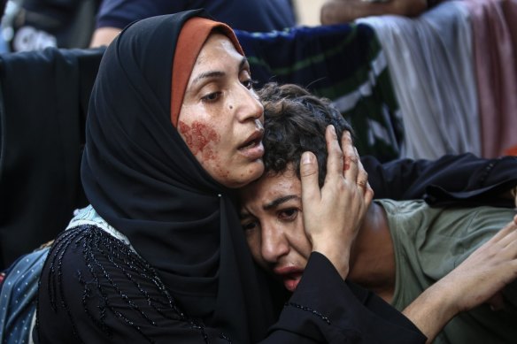 A Palestinian woman consoles a child following Israeli airstrikes on the al-Fakhoora district of Jabalia, northern Gaza on Saturday.