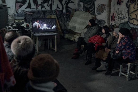 People watch religious Christmas films in an apartment block basement in Avdiivka, Ukraine. The TV, brought in by a local policeman and chaplain, relies on power from a generator.