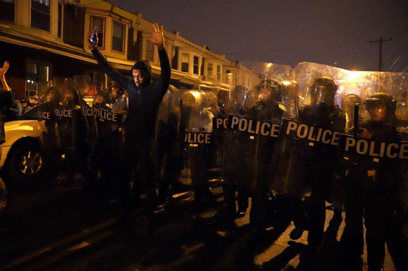 A man raises his arms in front of the police line during a protest in response to the police shooting of Walter Wallace.