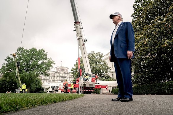 Trump watches on as the workers install new flagpoles.