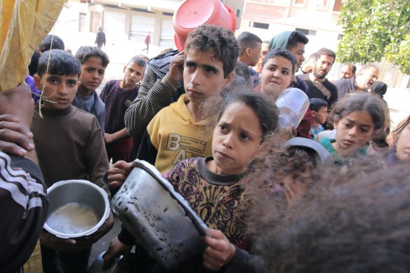 Displaced Palestinian children collect free food from a volunteer-run hospice near Nasser Medical Hospital in Gaza.