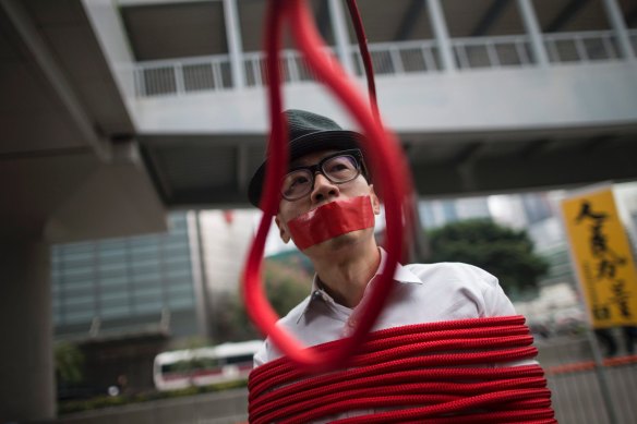 A protester stands in front of a noose that reads: "Kidnapping" during a protest against the disappearance of five booksellers in Hong Kong in 2016.