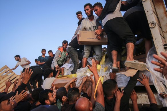 Palestinians distribute food aid that entered the southern Gaza Strip through the UN World Food Program in the Wadi Gaza area on Saturday.