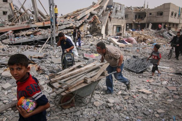 Palestinians recover firewood and useful items from the building rubble  in Al-Nuseirat camp, central Gaza Strip, on Thursday.