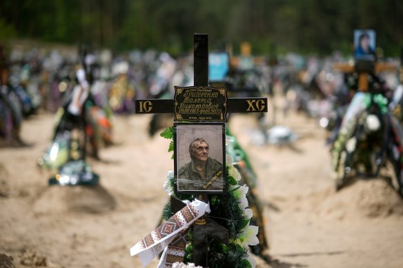 A photograph of one of victims of the battles for Irpin and Bucha adorns a cross as it stands among other crosses and floral tributes at Irpin cemetery.