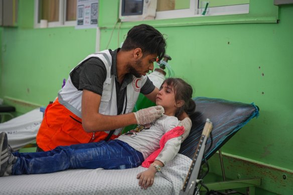 A medic treats an injured child after Israeli airstrikes in the Rimal district of Gaza City.