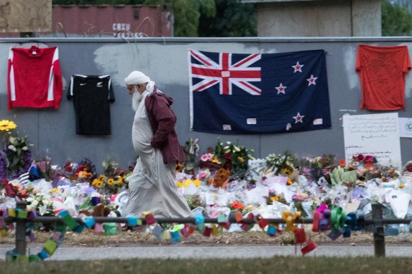 A Muslim man walks past a makeshift memorial on the walls surrounding the al-Noor Mosque.