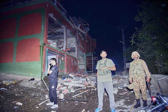 Security force officials stand outside a damaged building at a site of a suspected Indian missile attack near Muzaffarabad, the capital of Pakistan-administered Kashmir on May 7.