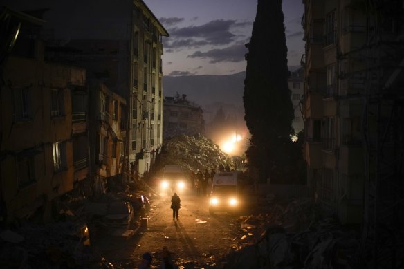 People walk among the rubble from destroyed buildings in Antakya, southern Turkey.