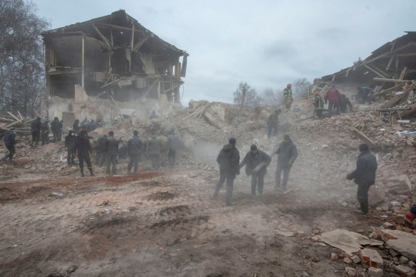 People remove debris at the site of a military base building that, according to the Ukrainian ground forces, was destroyed by an air strike, in the town of Okhtyrka in the Sumy region.