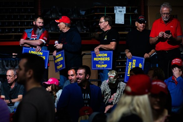 Attendees hold signs supporting former US President Donald Trump during a campaign event at Drake Enterprises in Clinton Township, Michigan
