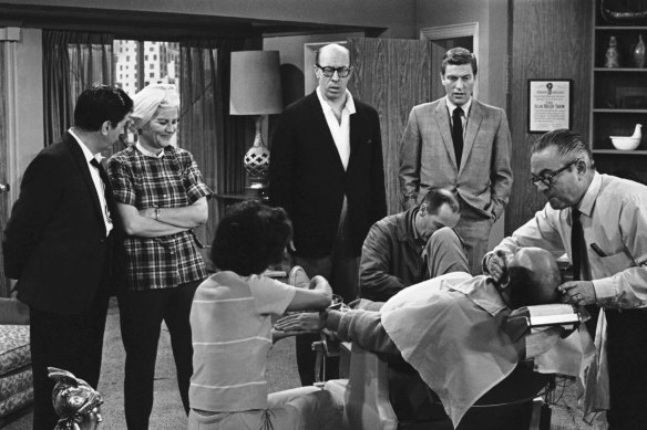 Standing, Morey Amsterdam (left), Rose Marie, Richard Deacon and Dick Van Dyke, right, watch Carl Reiner, in barber chair, during a rehearsal for the The Dick Van Dyke Show in 1963.
