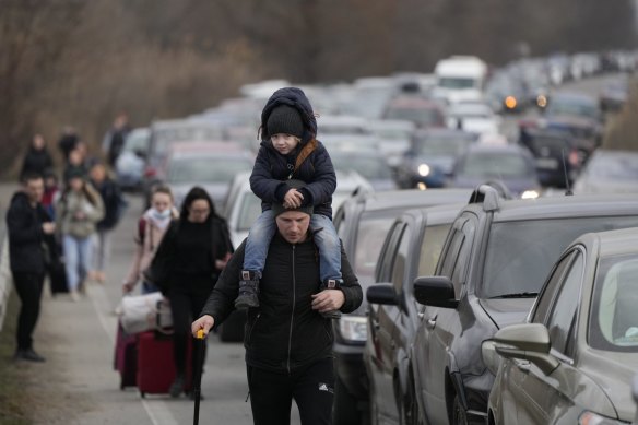 Ukrainian refugees walk alongside vehicles lining up to cross the border from Ukraine into Moldova on Saturday.