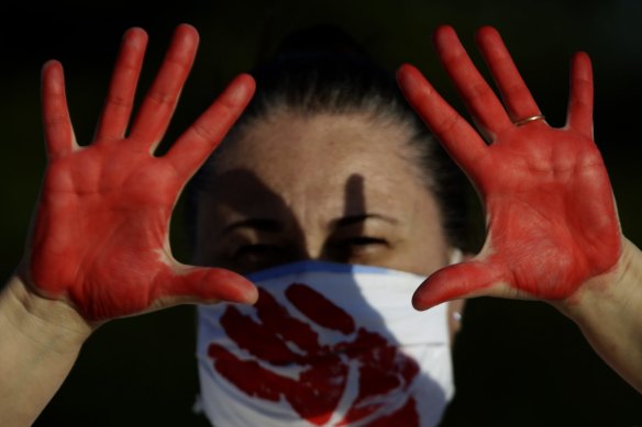A demonstrator shows her red-painted hands representing the blood of the more than 216,000 deaths from the COVID-19 pandemic in Brazil, during a protest against the government’s response in Brasilia on Sunday.