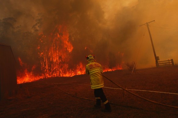 Firefighters battle to protect property from a bushfire on Lakes Way, north of Forster.