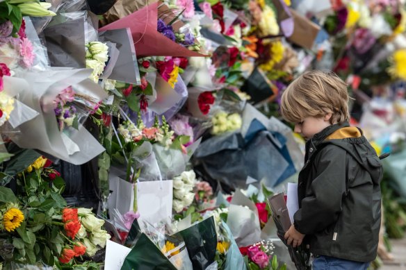 A young boy lays flowers outside Buckingham Palace.