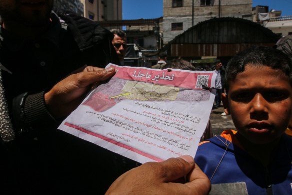 Palestinians read leaflets dropped by Israeli aircraft warning them to evacuate on Monday ahead of military operations in Rafah, Gaza.
