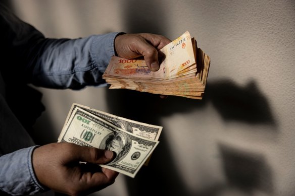 A money changer holds US hundred-dollar banknotes and 1000-peso banknotes in Buenos Aires, Argentina.