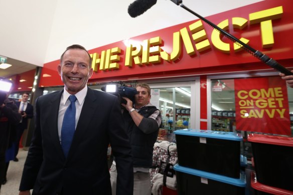 Then-prime minister Tony Abbott walks past The Reject Shop in 2015.