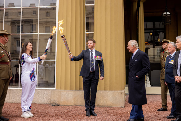 Torchbearer Angela Brient (left) and Corporal Daniel Keighran VC mark the start of the London leg of the Legacy relay at Buckingham Palace on Friday. The ceremony is watched by King Charles.