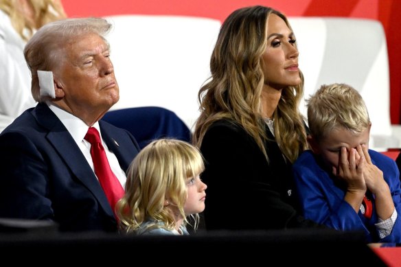 Former US president Donald Trump, sporting a bandage after his assassination attempt,  with his grandchildren and Lara Trump at the RNC in July.