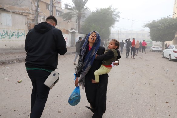 A Palestinian woman carries a child following an Israeli airstrike near the Kuwaiti hospital in Rafah, southern Gaza, on Wednesday.