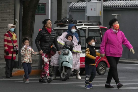 Residents, some wearing masks, cross a road in Beijing, China in October. 