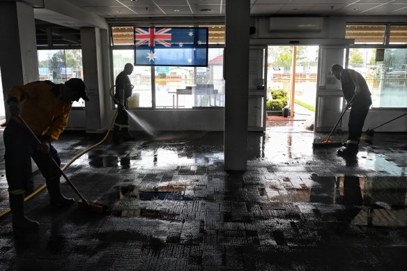 RFS crews pump and sweep out flood water from the Camden Sports Club on Friday. 