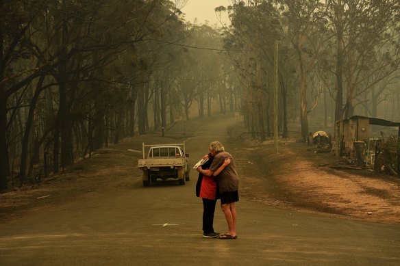 Residents comfort each other on Runniford Road in Nelligen where several homes and out buildings were destroyed or damaged in the fire near Batemans Bay.