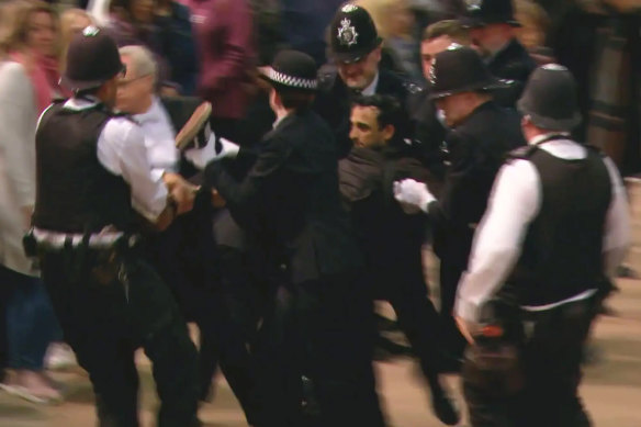 A screen grab of police at Westminster Hall wrestling a man to the ground after he rushed towards the Queen’s coffin and tried to pull at the flag draped over it.