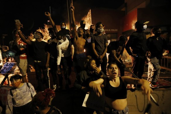 Protesters gather in front of the burning  third precinct station of the Minneapolis Police Department.