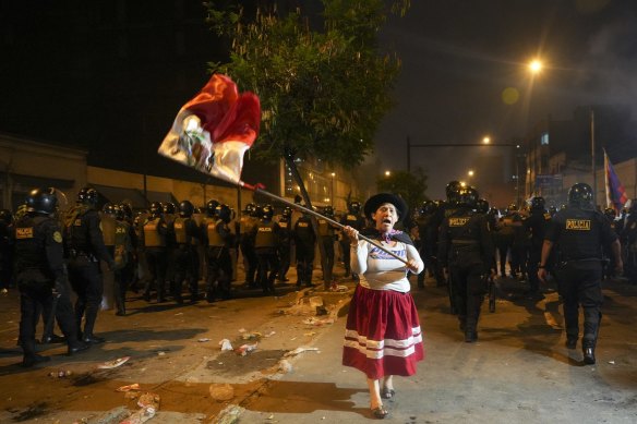 Cuma günü Lima'da hükümet karşıtı bir protesto sırasında bir kadın Peru bayrağı sallıyor.