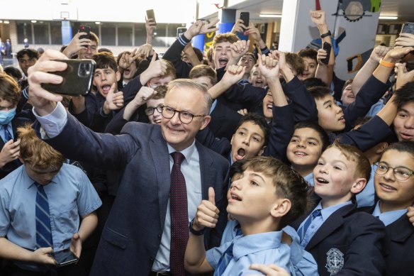 Anthony Albanese poses for a selfie with students during a visit to his old school during the campaign.