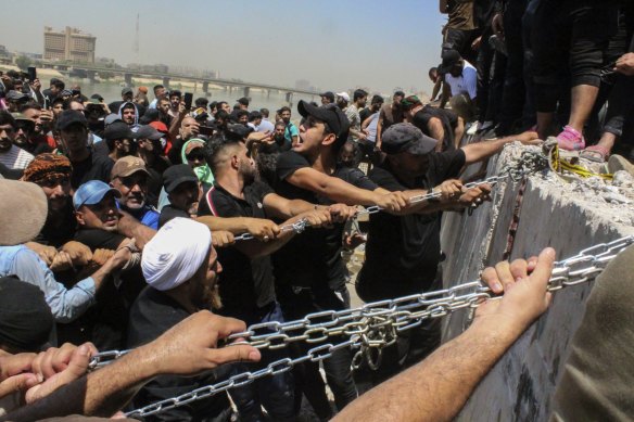 Protesters try to remove concrete barriers and cross the bridge towards the Green Zone area in Baghdad, Iraq, on Saturday, July 30.